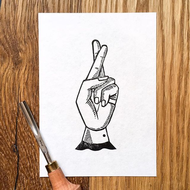 Linoprint image of a hand crossing its fingers